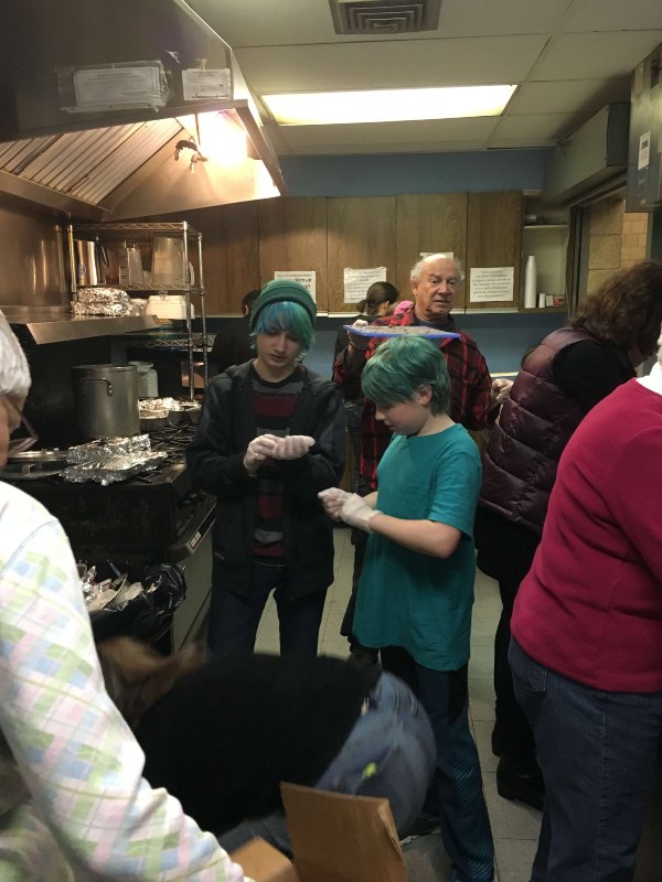 Teens and adults in kitchen preparing meals